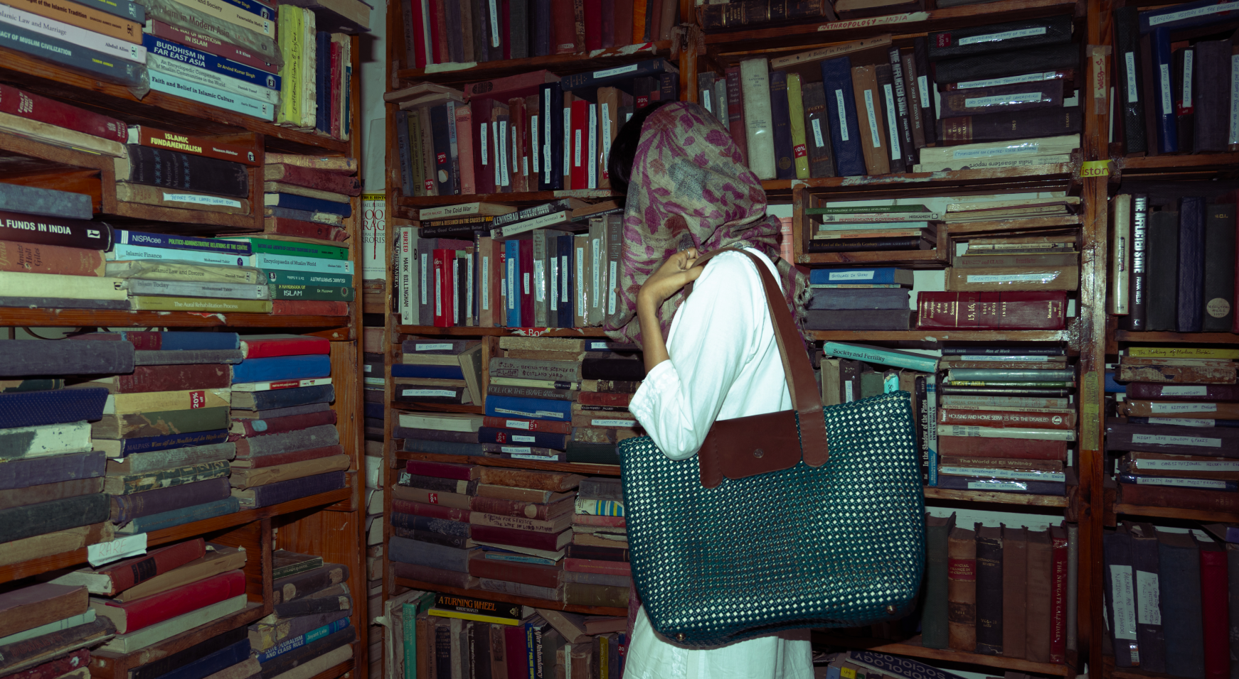 Person holding a large blue koodai kind bag in a room filled with bookshelves.